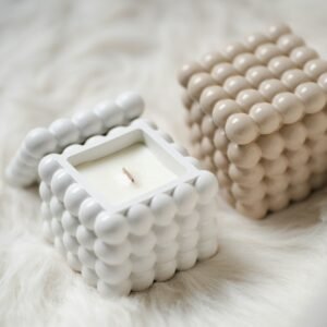 Bougies cubes à bulles, blanche et crème, posées sur une fourrure